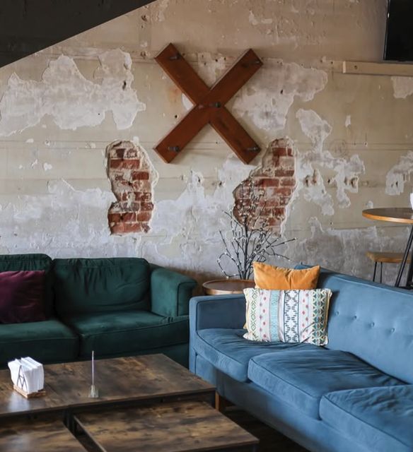 The lounge at The Local: a green sofa and a blue velvet couch against a plastered brick wall