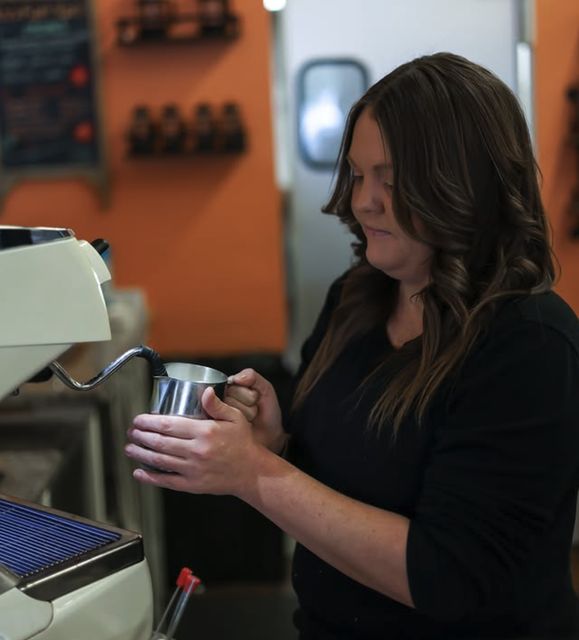 A barista steaming milk at the espresso machine