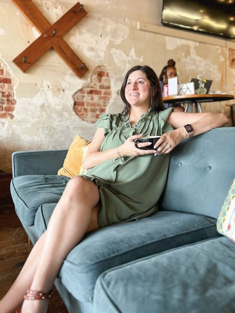 A guest with a coffee cup on the blue velvet couch