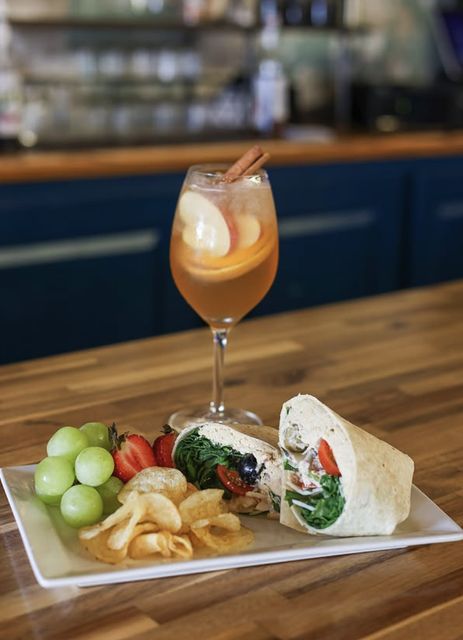 A turkey wrap with fruit, chips, and a glass of white sangria